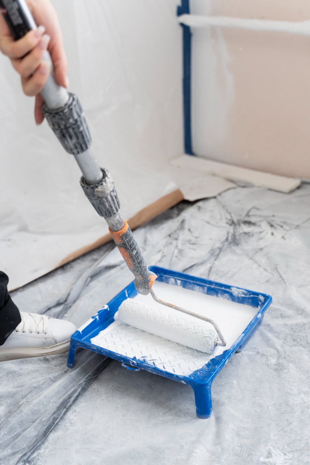 Paint roller and tray with the floor covered for interior painting