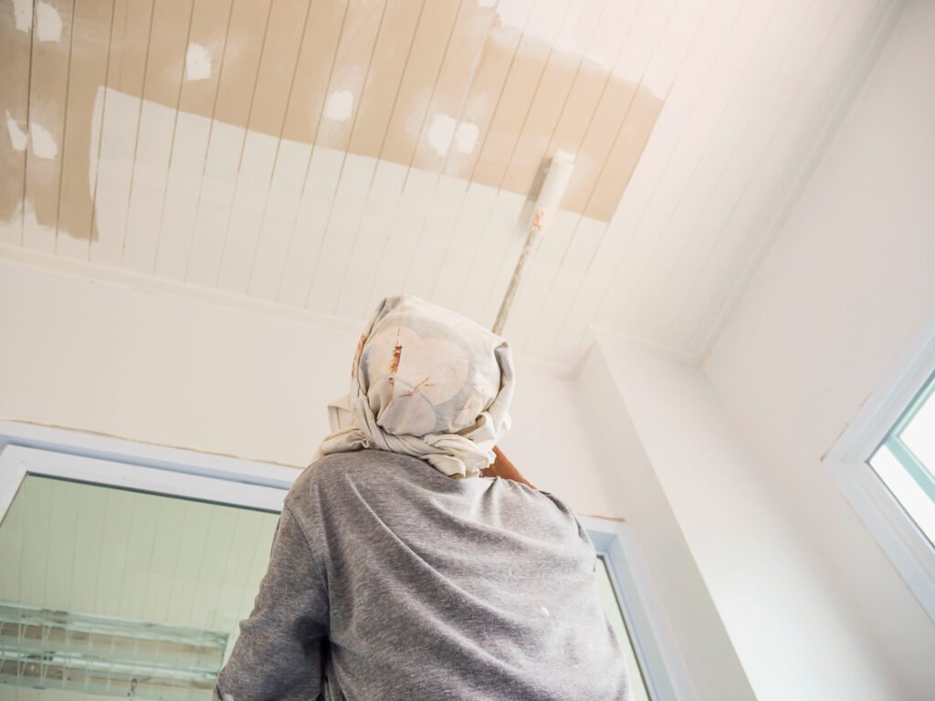 Painter applying white paint to a panelled ceiling
