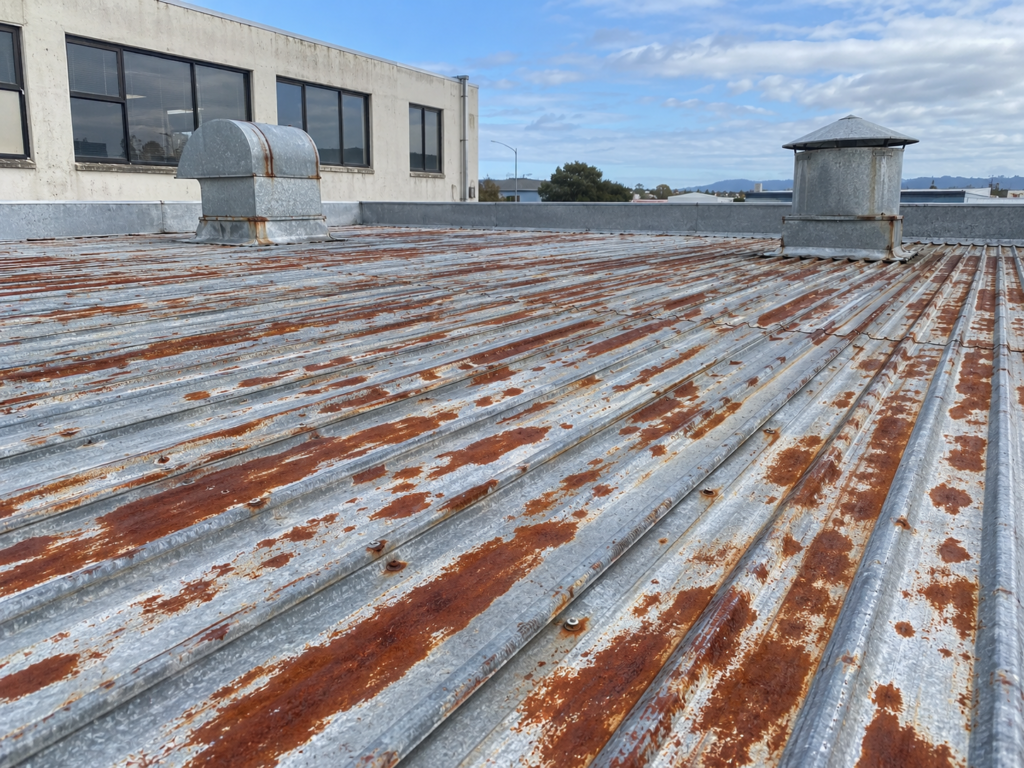 Weathered corrugated metal roofing with patches of rust and worn coating